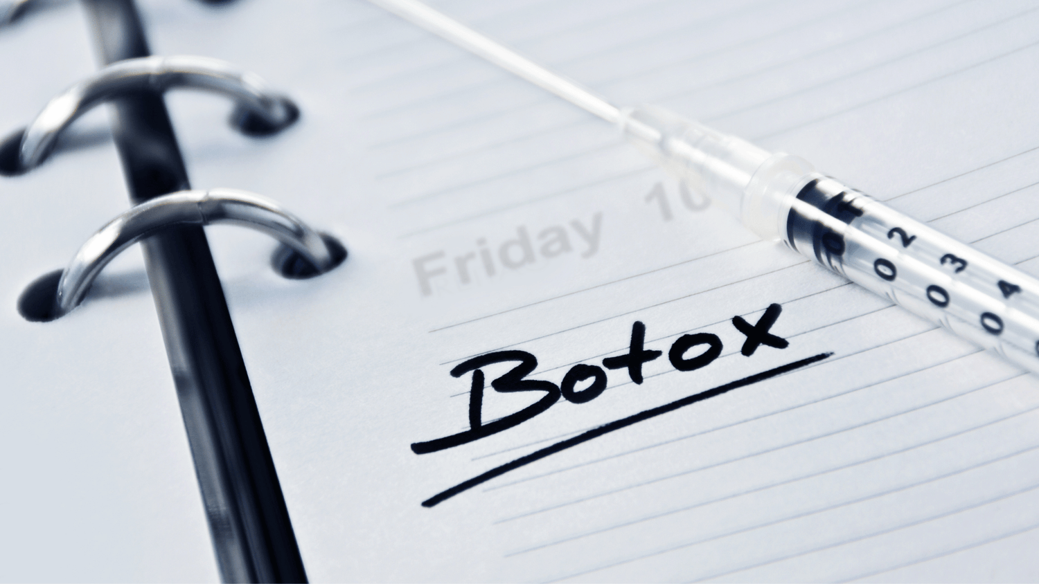 Photo of a notebook with the words Botox and a syringe laying across it