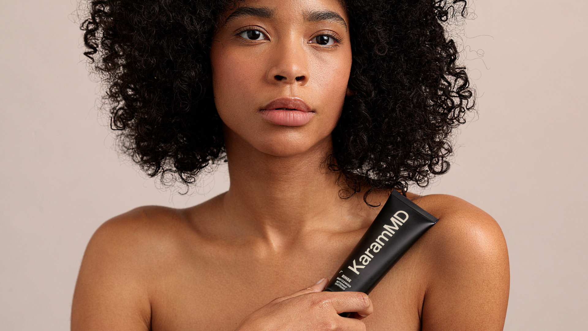 Woman holding up Rinse Daily Cleanser by KaramMD