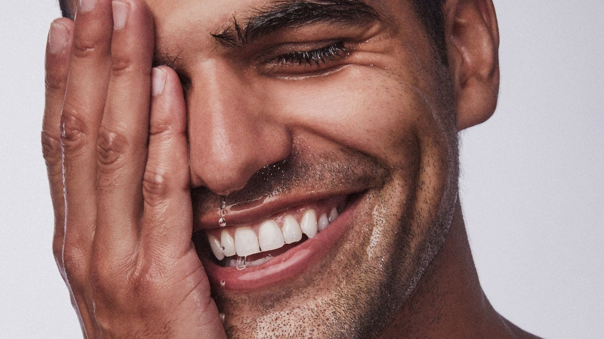 a smiling man cleansing his face