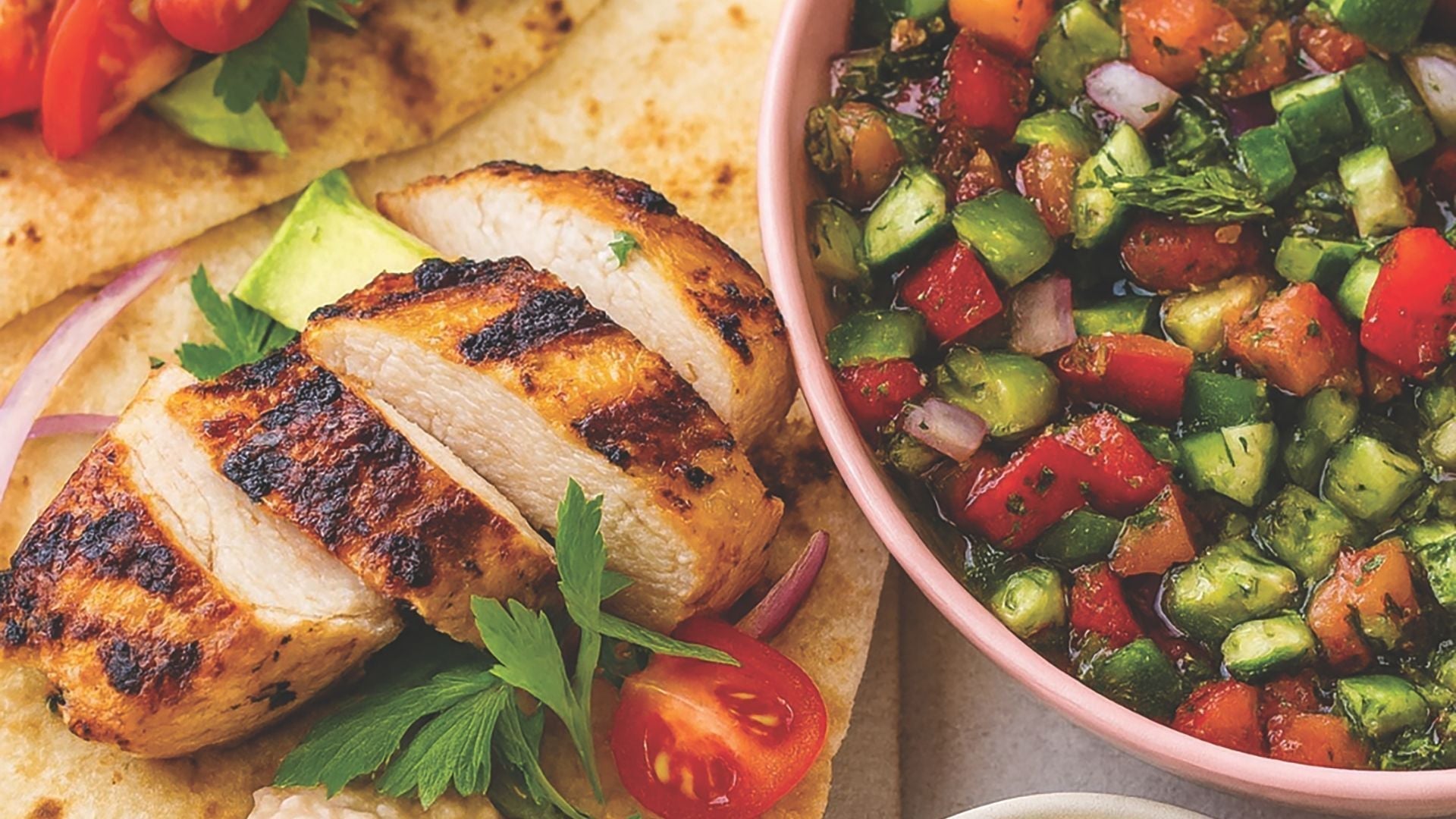 Grilled chicken over coals, bright persian salad from cucumbers, tomatoes, onion and lemon, on top of lavash bread for a delicious healthy meal your friends and family.