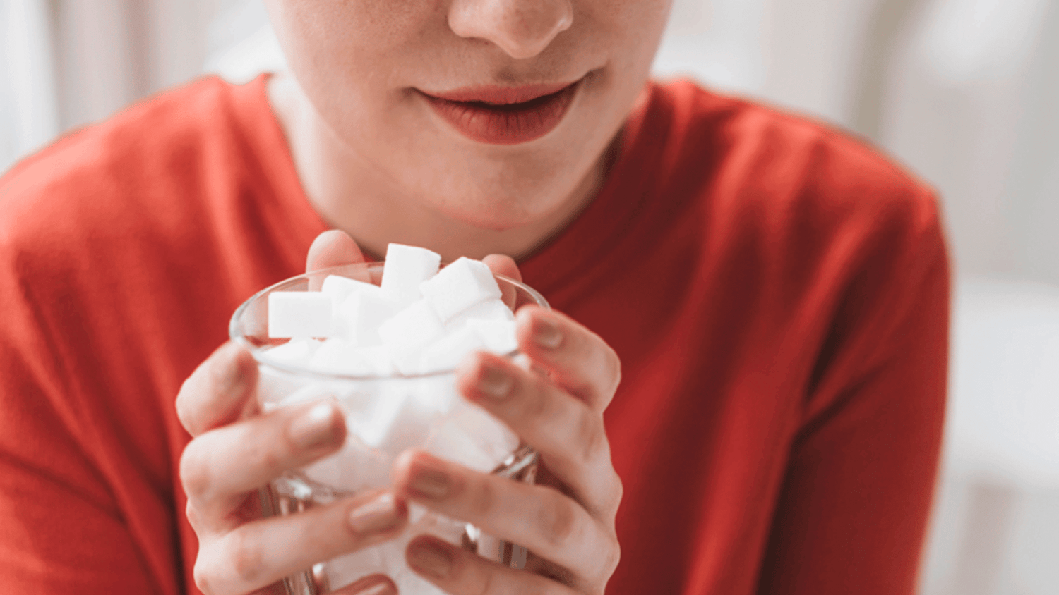 Woman holding a glass bowl filled with sugar cubes.