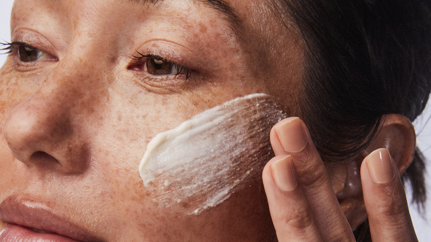 Woman putting on an exfoliator for smoother, brighter skin