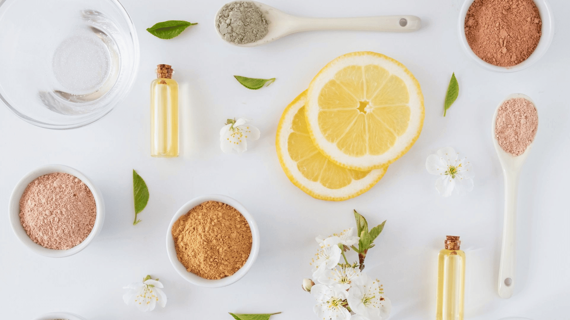 Flatlay of brightening skincare ingredients – lemon slices, facial powders, and botanical oils – used to treat and revive dull skin.