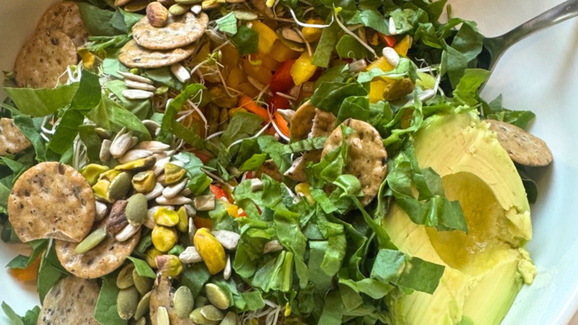 anti-aging salad with bell pepper, leafy green, avocado, broccoli seed sprouts, multiseed crackers