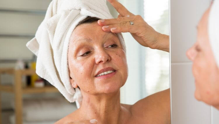 mature adult woman applying an anti-aging skincare routine to healthy youthful-looking skin