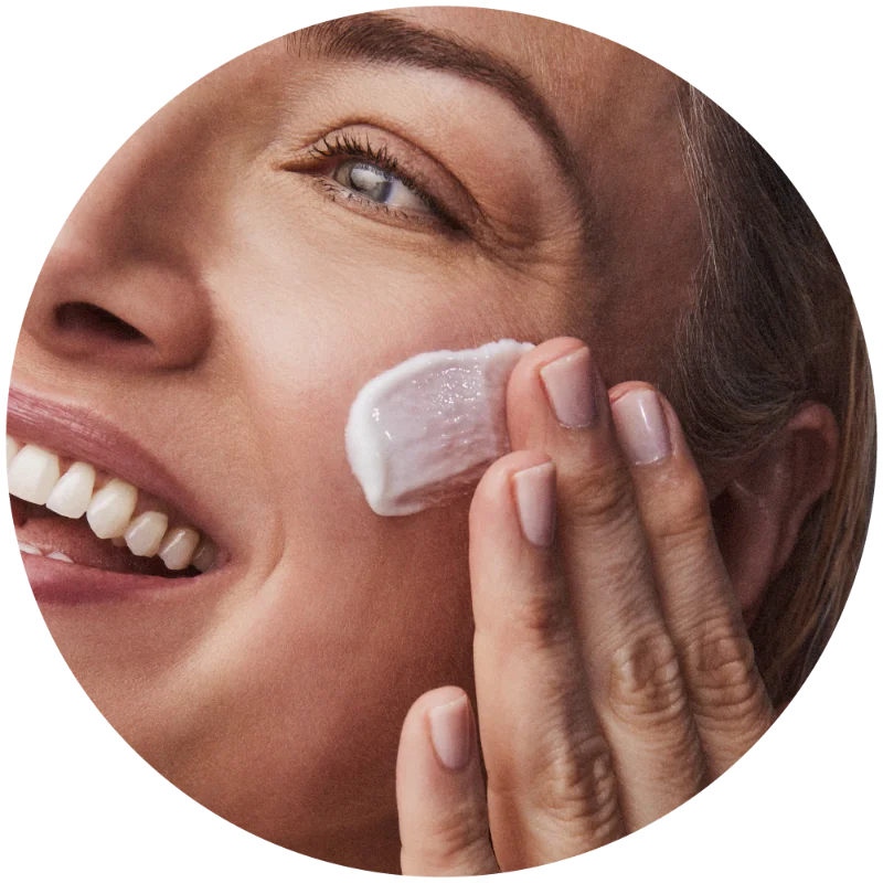 Woman applying cream to her face with a close-up view